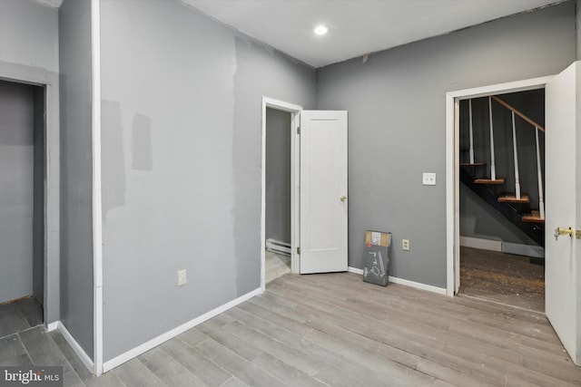 unfurnished bedroom featuring a baseboard radiator and light hardwood / wood-style flooring