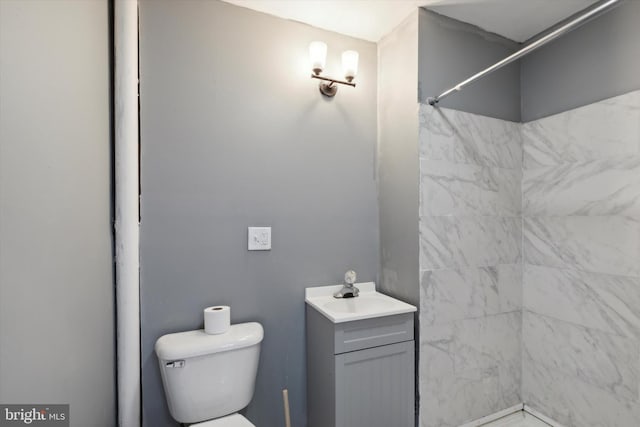 bathroom featuring tiled shower, vanity, and toilet