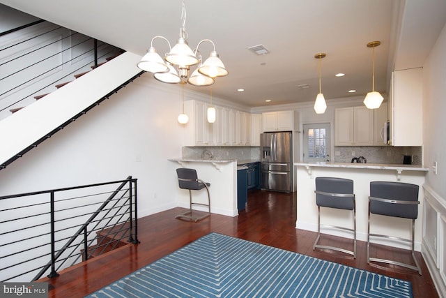 kitchen featuring hanging light fixtures, kitchen peninsula, stainless steel appliances, dark hardwood / wood-style floors, and a breakfast bar area