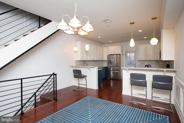 kitchen with a breakfast bar area, stainless steel appliances, kitchen peninsula, and white cabinetry