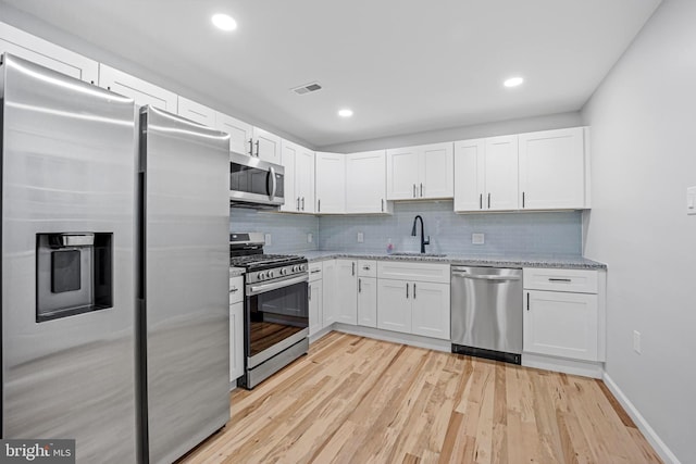 kitchen with stainless steel appliances, light wood-type flooring, sink, and white cabinetry