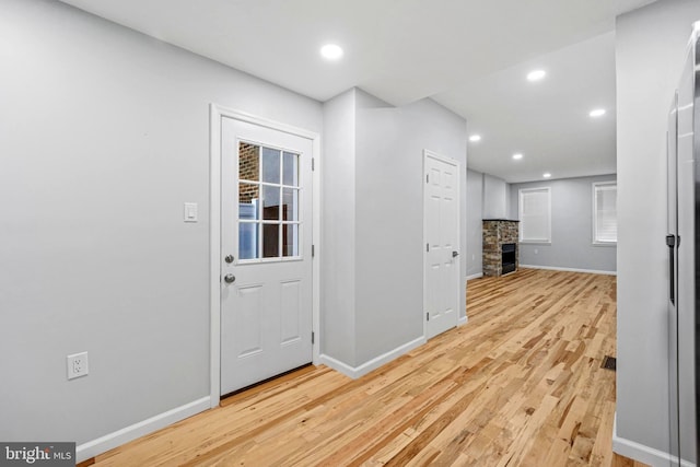 entrance foyer featuring light wood-type flooring and a stone fireplace