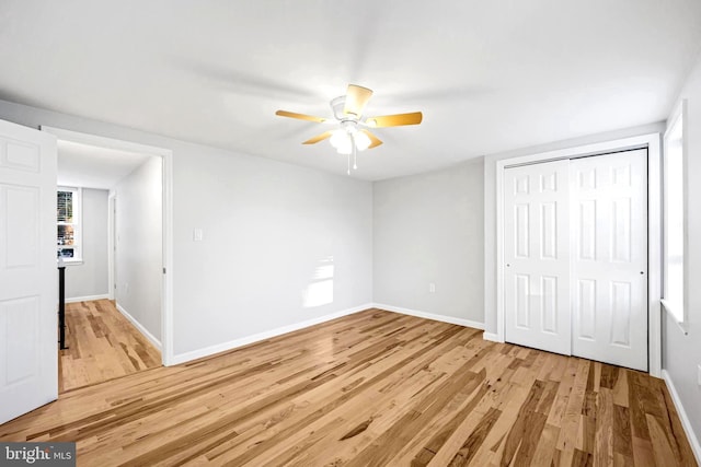 unfurnished bedroom with light wood-type flooring, ceiling fan, and a closet