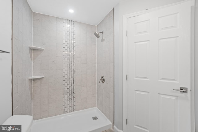 bathroom featuring a tile shower and toilet