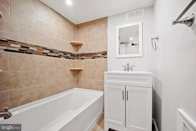 bathroom with tile patterned flooring, vanity, and tiled shower / bath