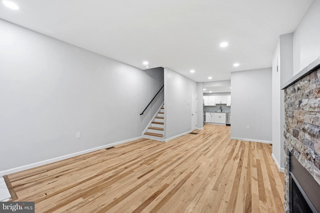 unfurnished living room with a fireplace, sink, and light hardwood / wood-style flooring