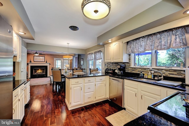 kitchen featuring dark hardwood / wood-style floors, kitchen peninsula, hanging light fixtures, decorative backsplash, and stainless steel dishwasher