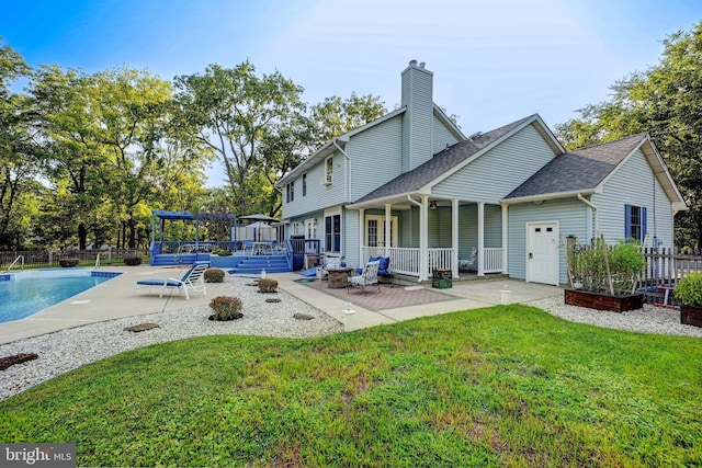 back of house with a yard, a fenced in pool, and a patio area