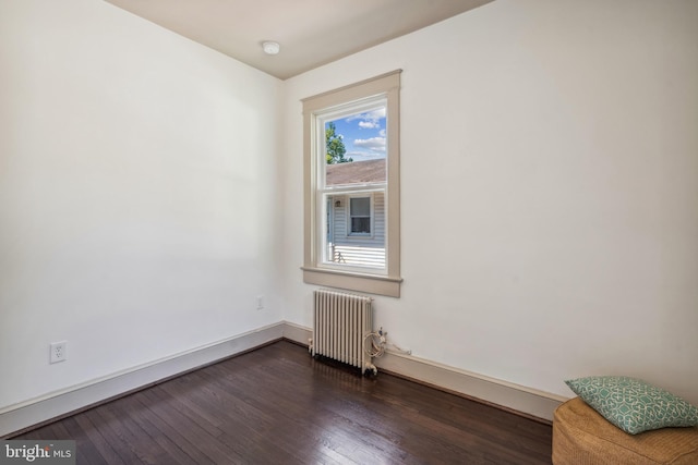 empty room with dark wood-type flooring and radiator heating unit