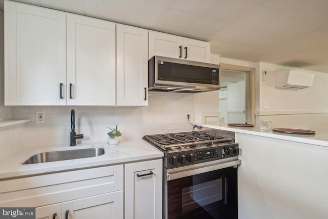 kitchen with tasteful backsplash, sink, white cabinetry, stainless steel appliances, and light stone countertops