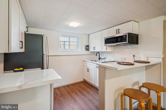 kitchen featuring a breakfast bar, white cabinets, appliances with stainless steel finishes, and light hardwood / wood-style flooring