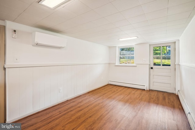 spare room featuring wood-type flooring, a wall mounted air conditioner, and a baseboard radiator