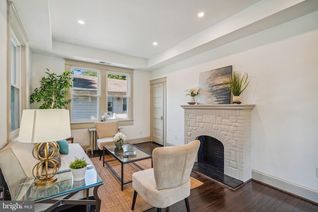 living room with hardwood / wood-style floors, a tray ceiling, and a fireplace