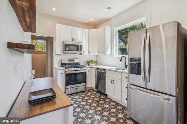 kitchen with backsplash, white cabinetry, appliances with stainless steel finishes, and sink