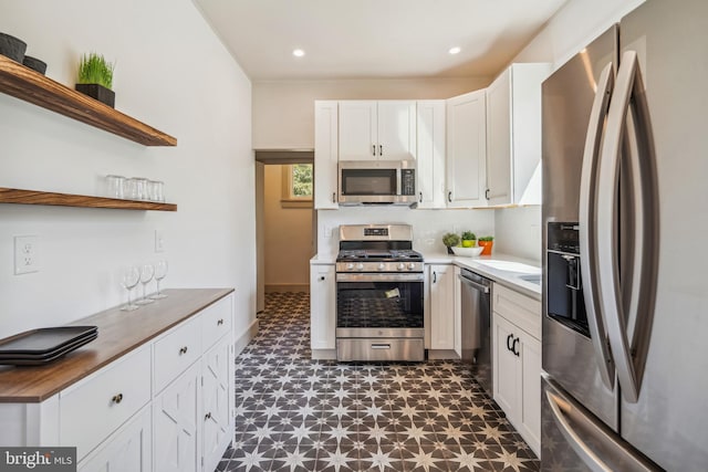 kitchen featuring tasteful backsplash, butcher block countertops, stainless steel appliances, and white cabinets