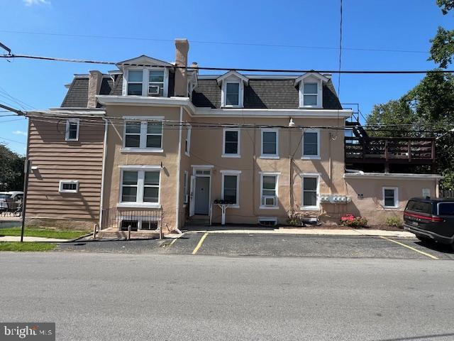 view of front of home with mansard roof and uncovered parking