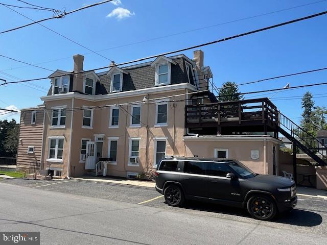 view of front of property featuring mansard roof, stucco siding, and stairway