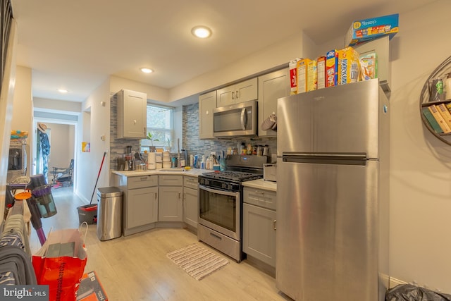 kitchen featuring gray cabinetry, stainless steel appliances, tasteful backsplash, and light hardwood / wood-style flooring