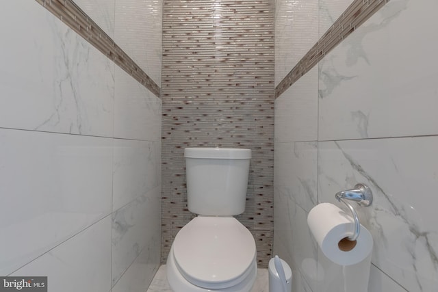 bathroom featuring toilet and tile walls