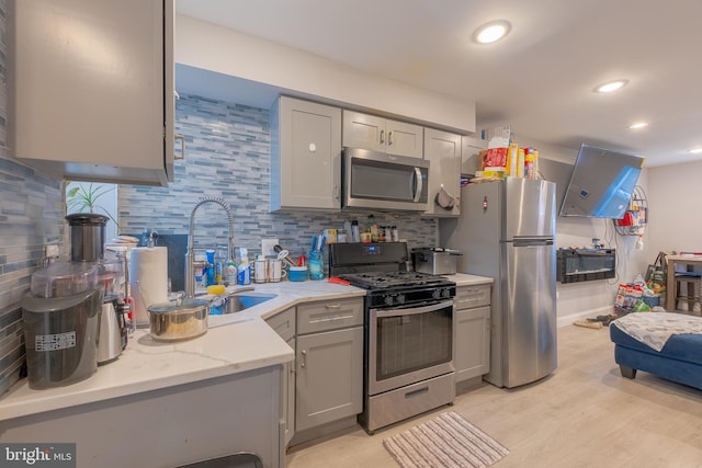 kitchen with gray cabinets, stainless steel appliances, sink, and light hardwood / wood-style floors