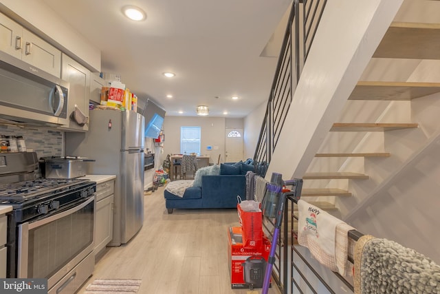 kitchen with appliances with stainless steel finishes, light wood-type flooring, and tasteful backsplash