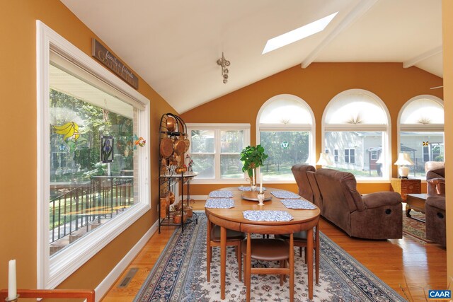 dining room featuring vaulted ceiling with skylight and hardwood / wood-style flooring