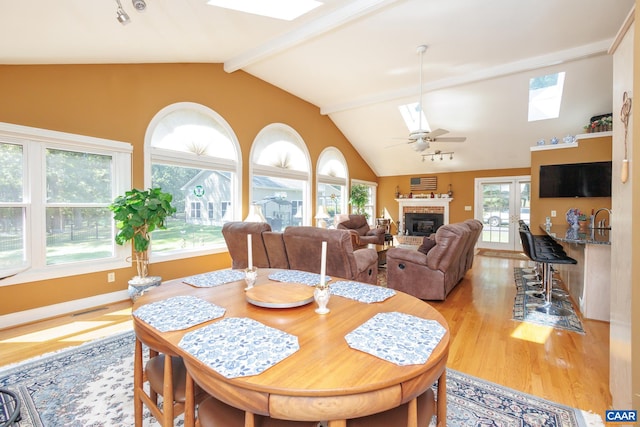 dining space featuring light hardwood / wood-style flooring, vaulted ceiling with skylight, french doors, and ceiling fan