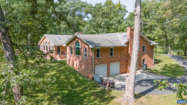 view of front of house with cooling unit, a garage, and a front lawn