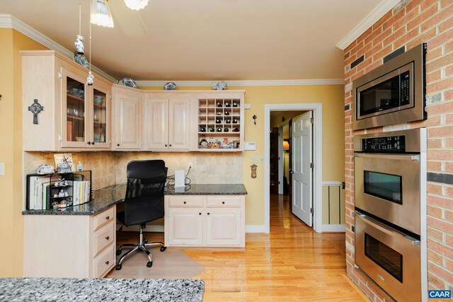 home office featuring light wood-type flooring, built in desk, and crown molding