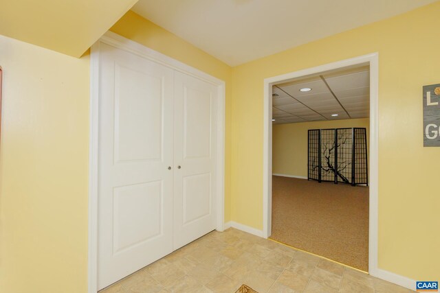 hallway featuring a paneled ceiling and light colored carpet