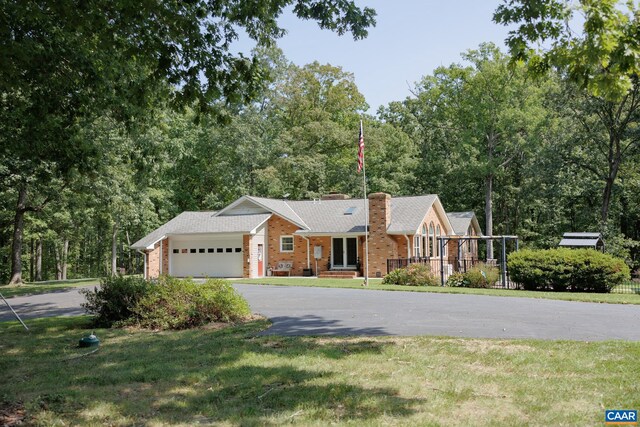 view of front of property with covered porch, a garage, and a front lawn