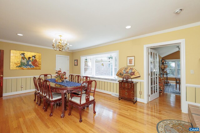 dining area with lofted ceiling, ornamental molding, a chandelier, and light hardwood / wood-style floors