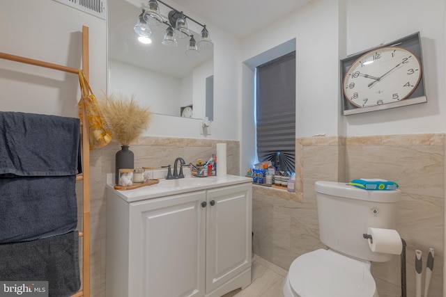 bathroom with vanity, toilet, tile walls, and tile patterned flooring