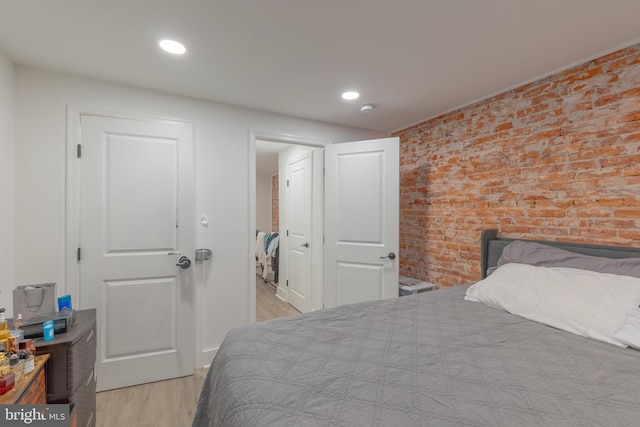 bedroom featuring light hardwood / wood-style floors and brick wall