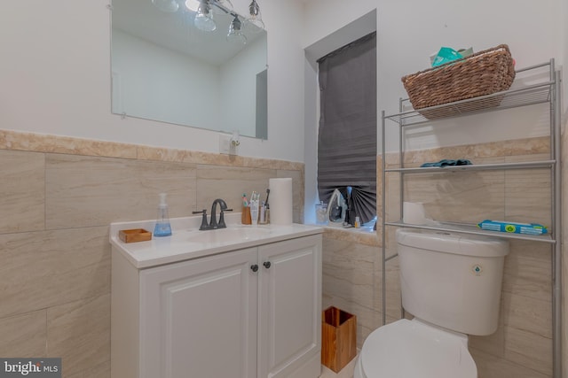 bathroom with tile walls, vanity, and toilet