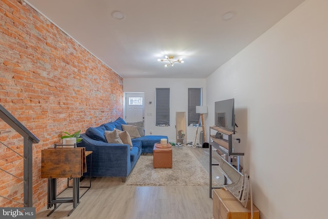 living room with light hardwood / wood-style floors and brick wall