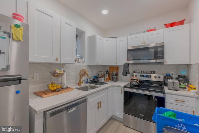 kitchen with decorative backsplash, appliances with stainless steel finishes, and white cabinetry