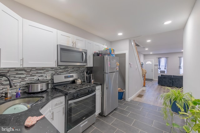 kitchen with stainless steel appliances, sink, dark stone counters, and white cabinets