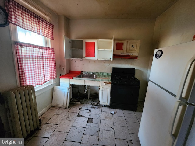 kitchen featuring black gas range, sink, white fridge, a healthy amount of sunlight, and radiator heating unit