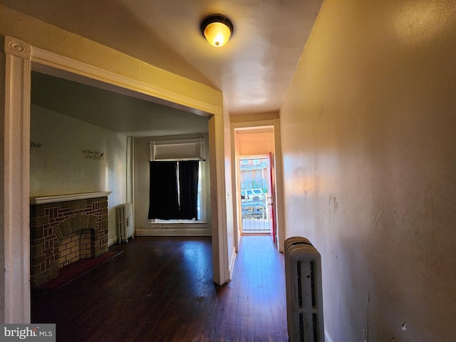 hallway with radiator heating unit, dark hardwood / wood-style floors, and lofted ceiling