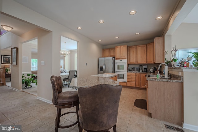 kitchen with light stone countertops, double oven, sink, and stainless steel fridge with ice dispenser