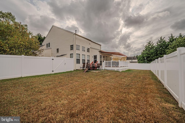 back of property featuring a lawn and a wooden deck