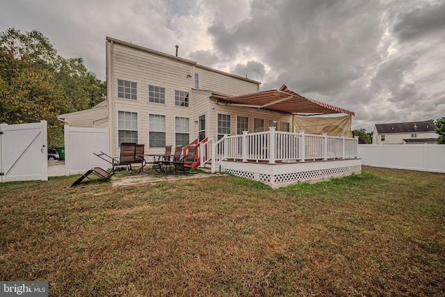 rear view of property featuring a wooden deck, a patio, and a yard