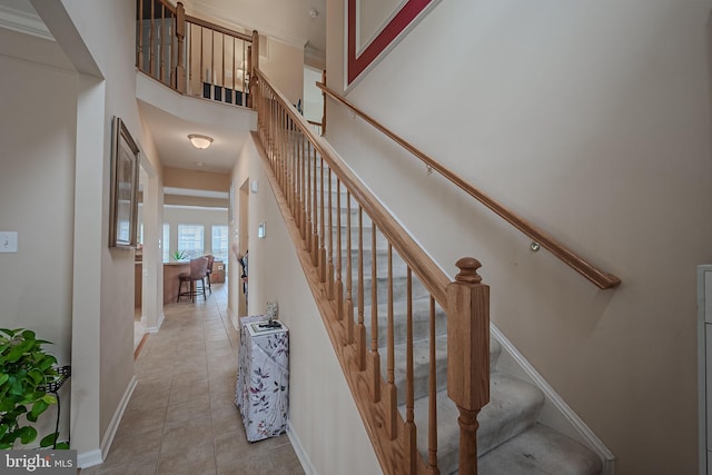 staircase with tile patterned flooring and a high ceiling