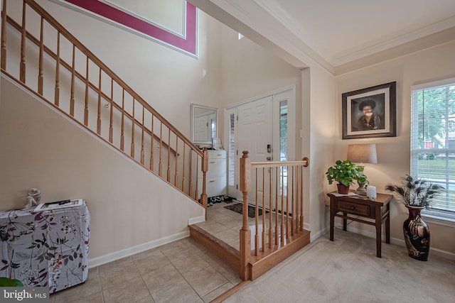 foyer with crown molding and light carpet