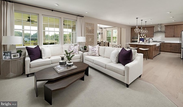 living room with light wood-type flooring, a wealth of natural light, and a notable chandelier