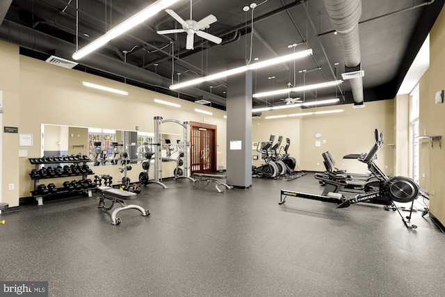 gym featuring a towering ceiling and ceiling fan