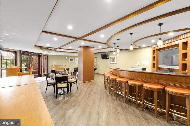 bar featuring light wood-type flooring, beamed ceiling, and decorative light fixtures