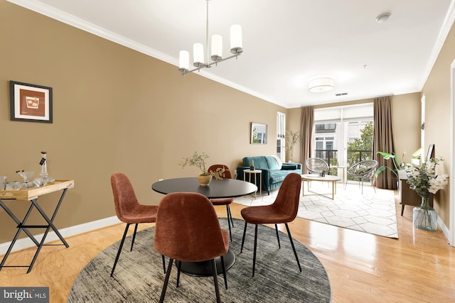 dining area featuring light hardwood / wood-style floors, ornamental molding, and a notable chandelier