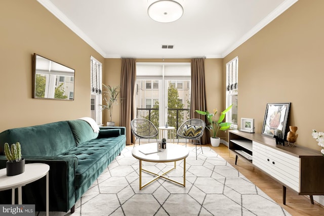 living room with light wood-type flooring, a healthy amount of sunlight, and ornamental molding